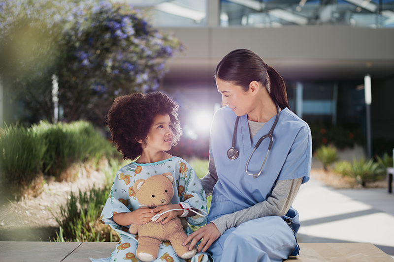 Professionnel de la santé en compagnie d’un jeune patient tenant un ours en peluche.